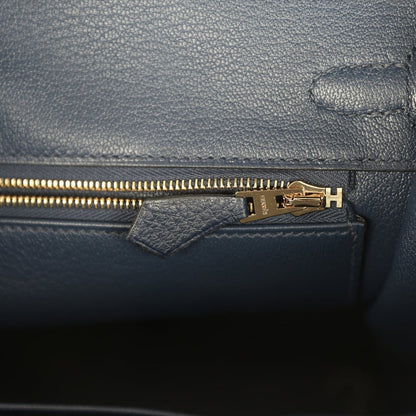 Gold zipper pull on blue Togo leather inner pocket with stamped hardware plate