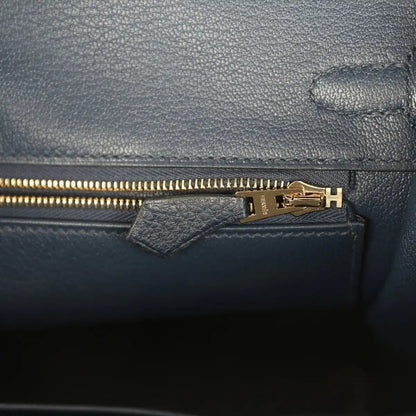 Gold zipper pull on blue Togo leather inner pocket with stamped hardware plate