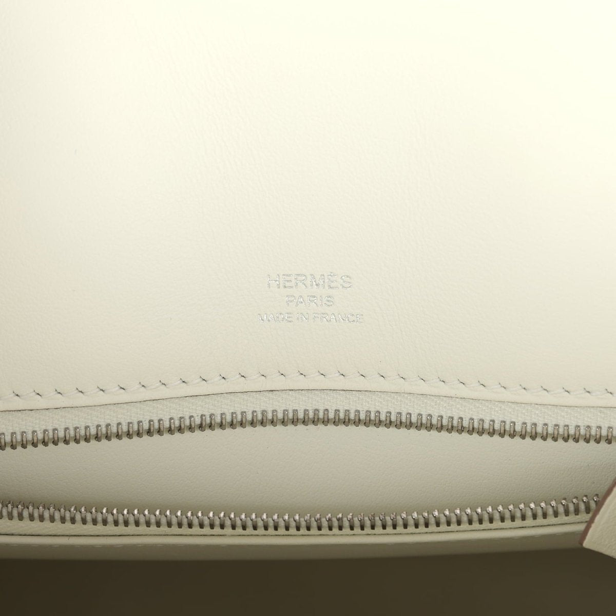 Hermes Paris logo embossed on cream lining above zipper track in leather handbag.