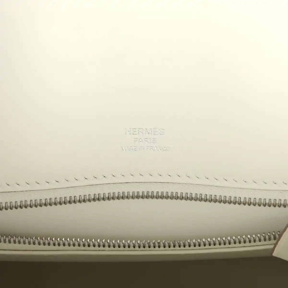 Hermes Paris logo embossed on cream lining above zipper track in leather handbag.