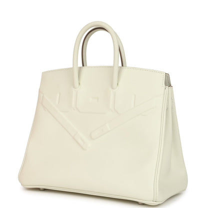 Cream leather handbag with embossed panel and side seam, top handles visible.