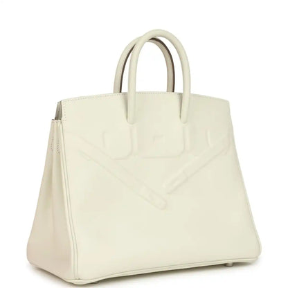 Cream leather handbag with embossed pattern and top handles, angled side view.