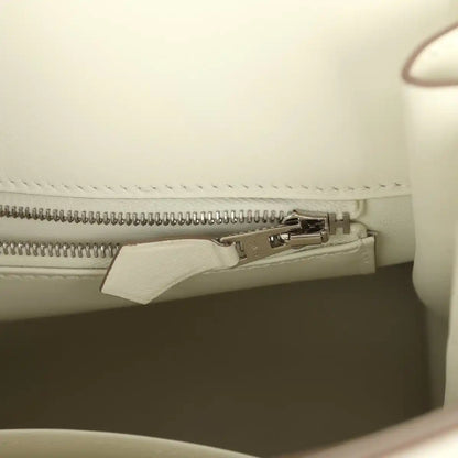 Cream leather handbag interior close-up of zipper track with metal pull tab.
