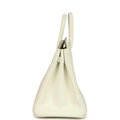 Cream leather handbag with open top showing stitched interior and short handles.