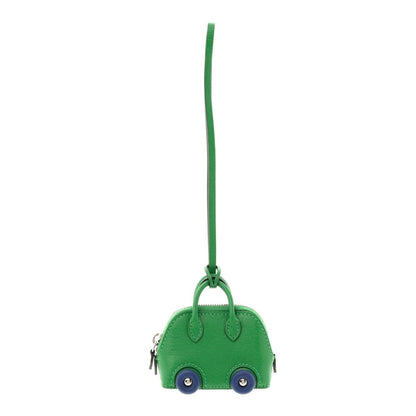 Green bag charm with long hanging strap, small wheels and blue button eyes