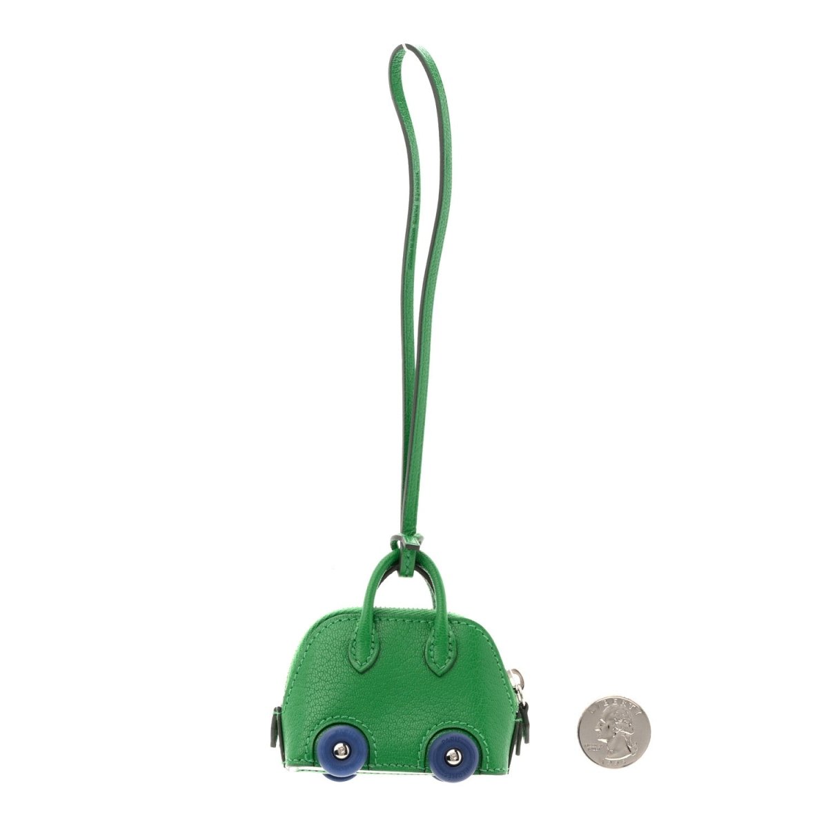 Green leather bag charm with loop strap, wheels and blue eyes; small coin for scale