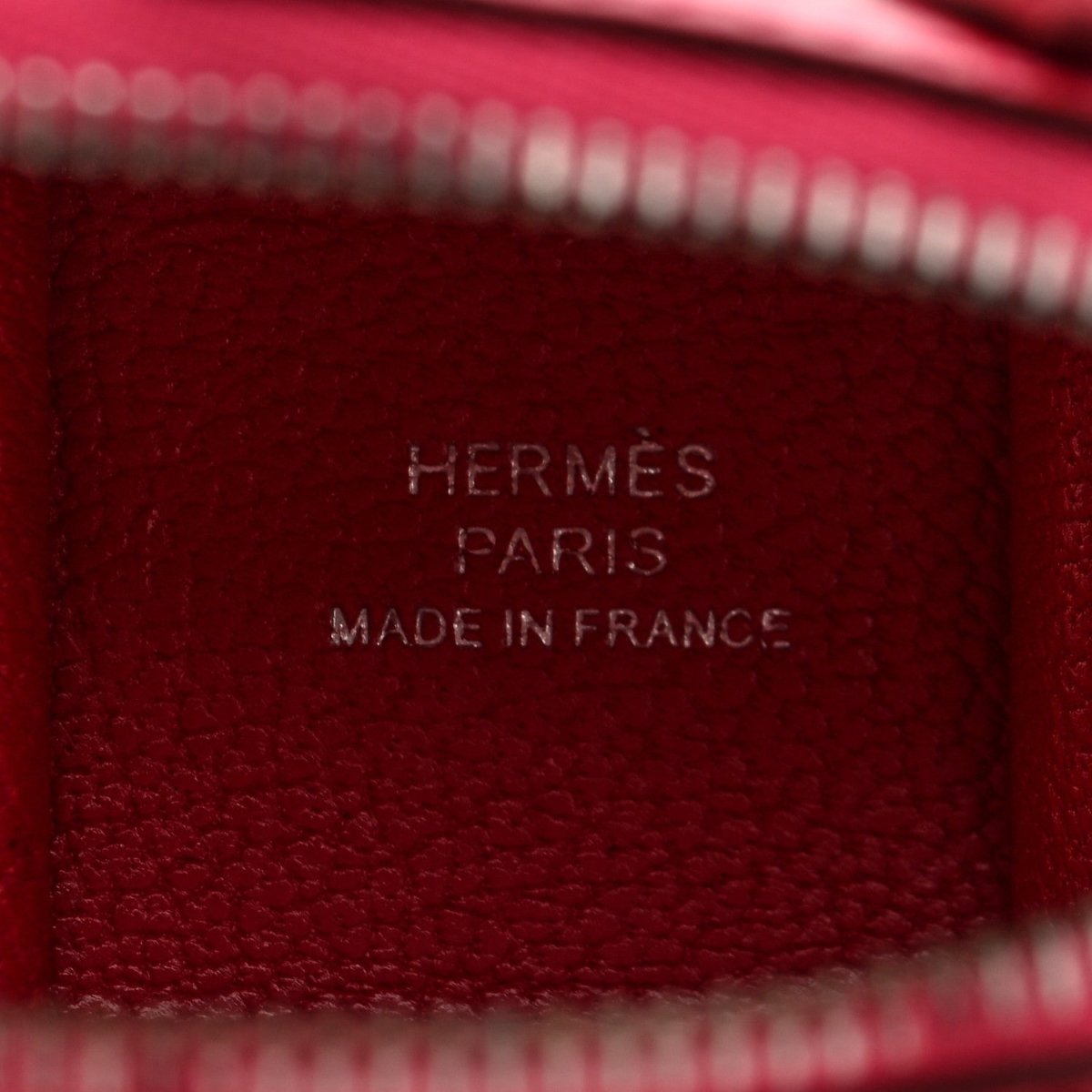 Red leather bag charm close-up with stamped HERMÈS PARIS MADE IN FRANCE
