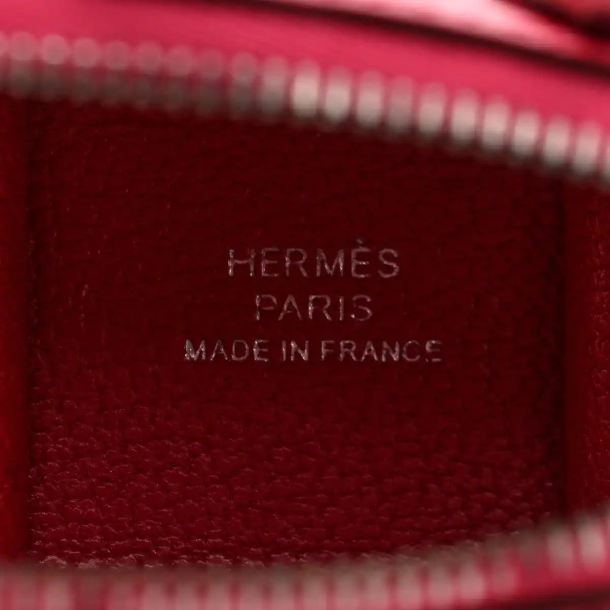 Red leather bag charm close-up with stamped HERMÈS PARIS MADE IN FRANCE