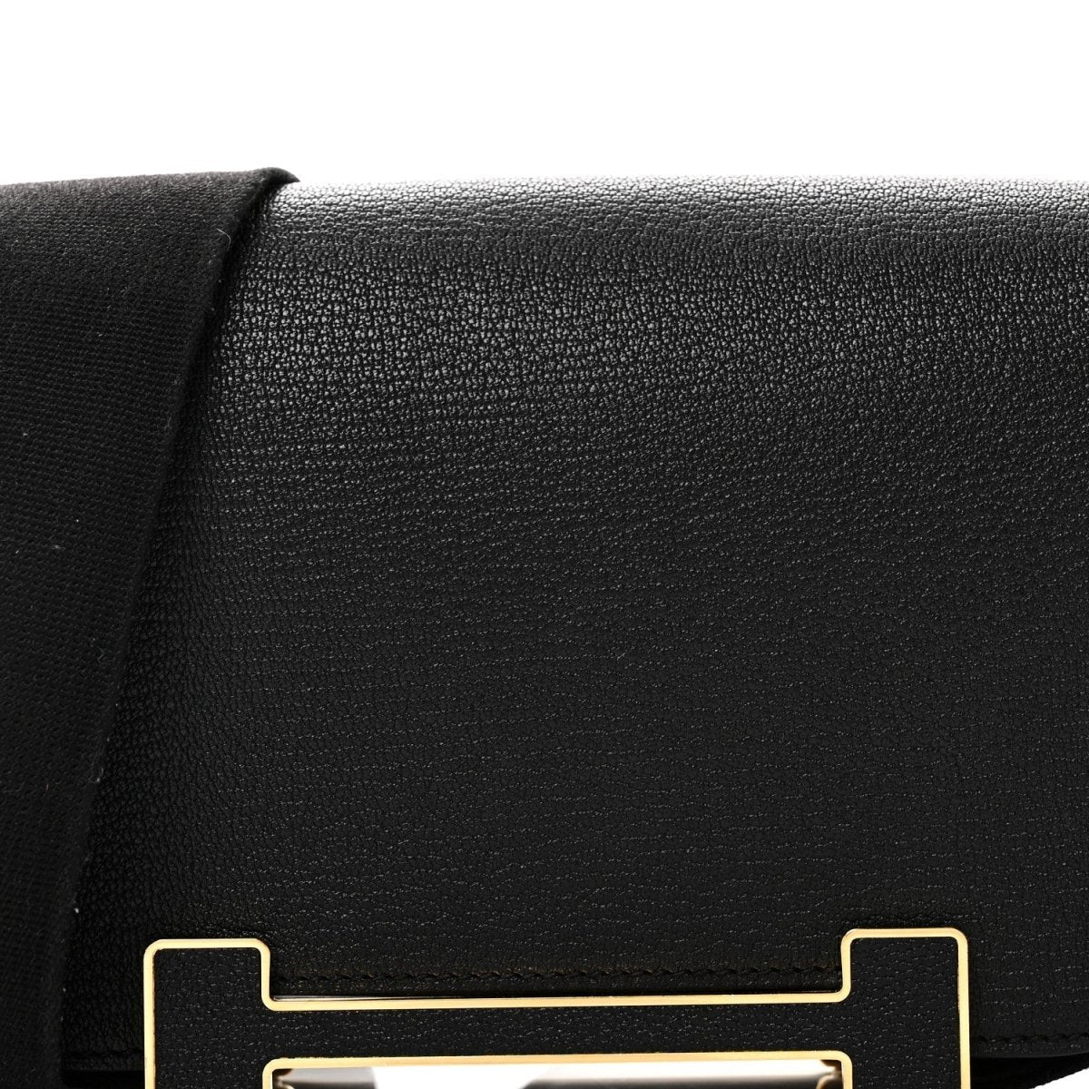 Hermes black leather crossbody bag flap with gold-tone clasp detail
