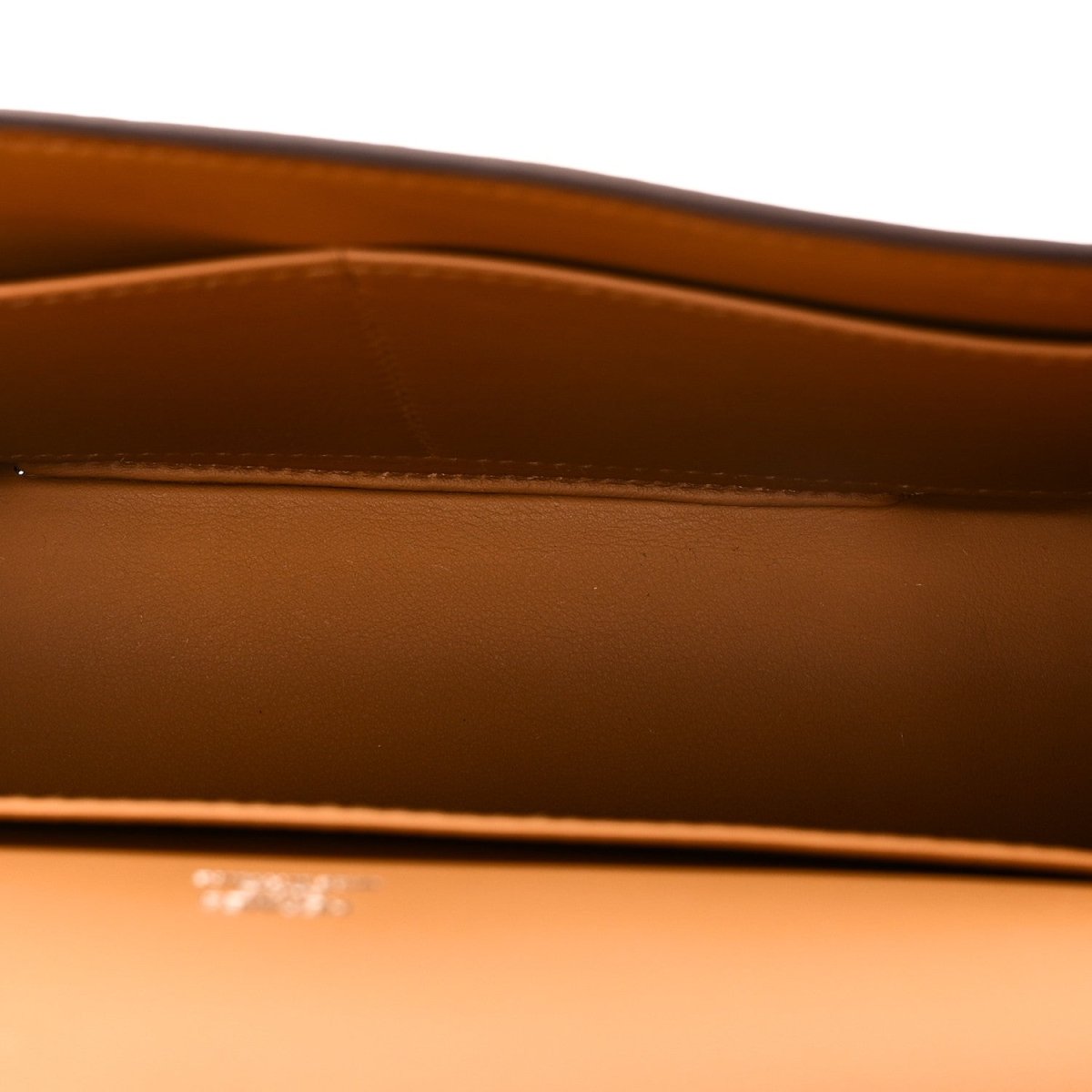 Caramel leather bag interior panel with embossed branding and top edge stitching detail