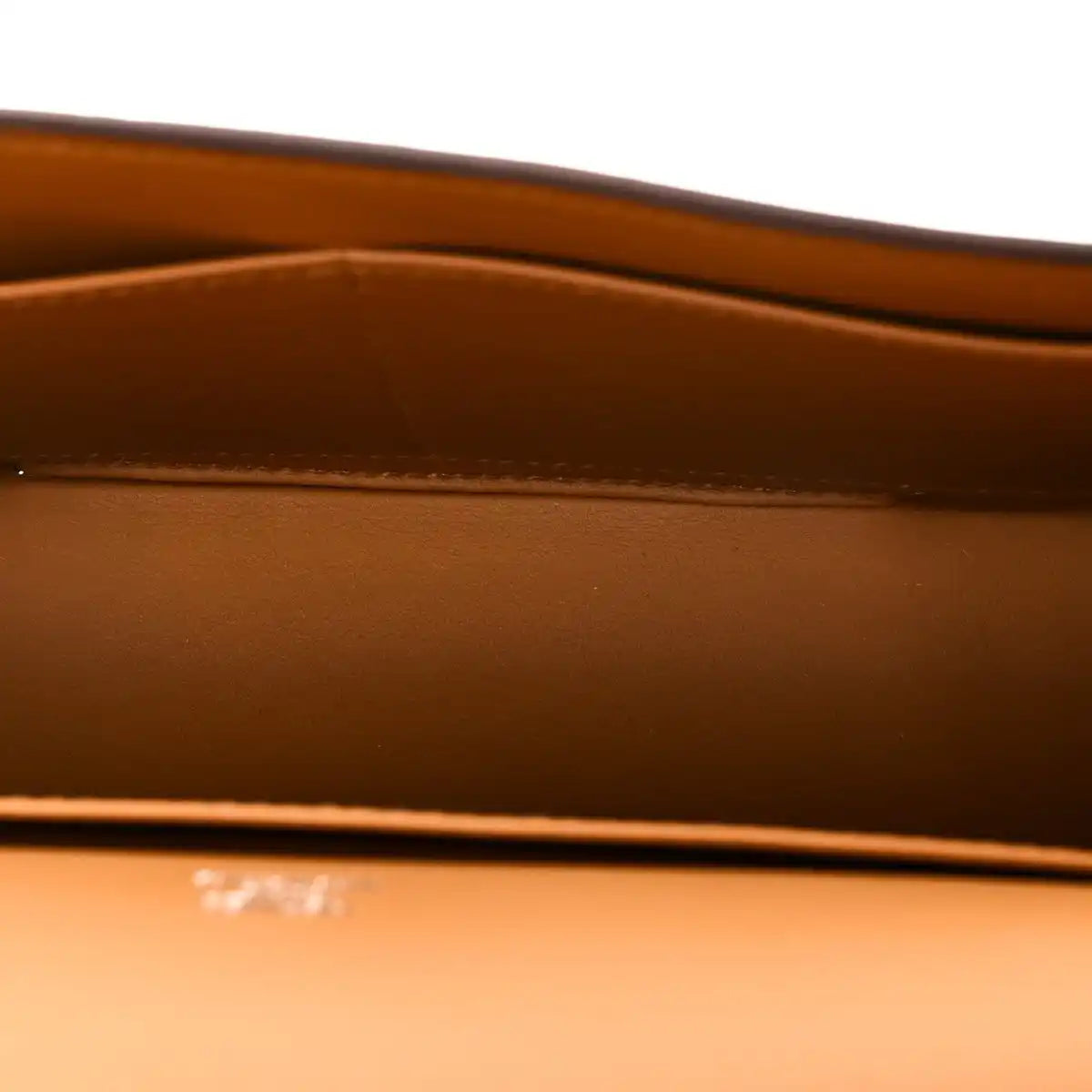 Caramel leather bag interior panel with embossed branding and top edge stitching detail