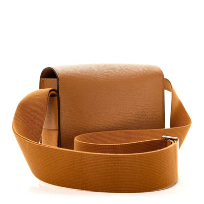 Caramel leather messenger bag with front flap and wide webbing strap, side view