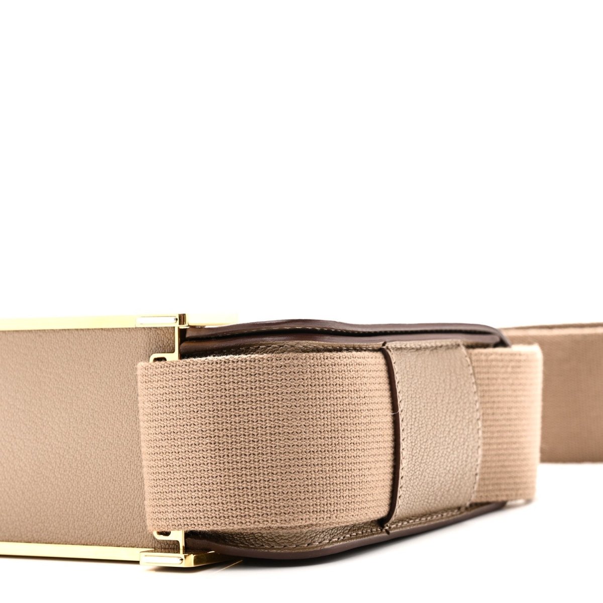 Close-up of taupe messenger bag flap and wide canvas strap with gold hardware