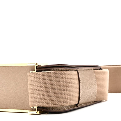 Close-up of taupe messenger bag flap and wide canvas strap with gold hardware