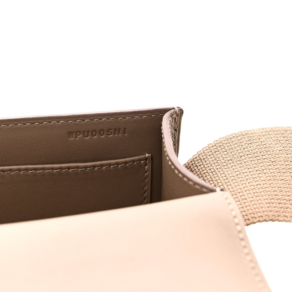 Close-up of taupe leather messenger bag label and stitched edge with strap