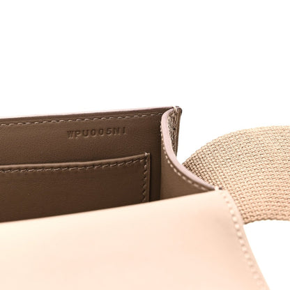 Close-up of taupe leather messenger bag label and stitched edge with strap
