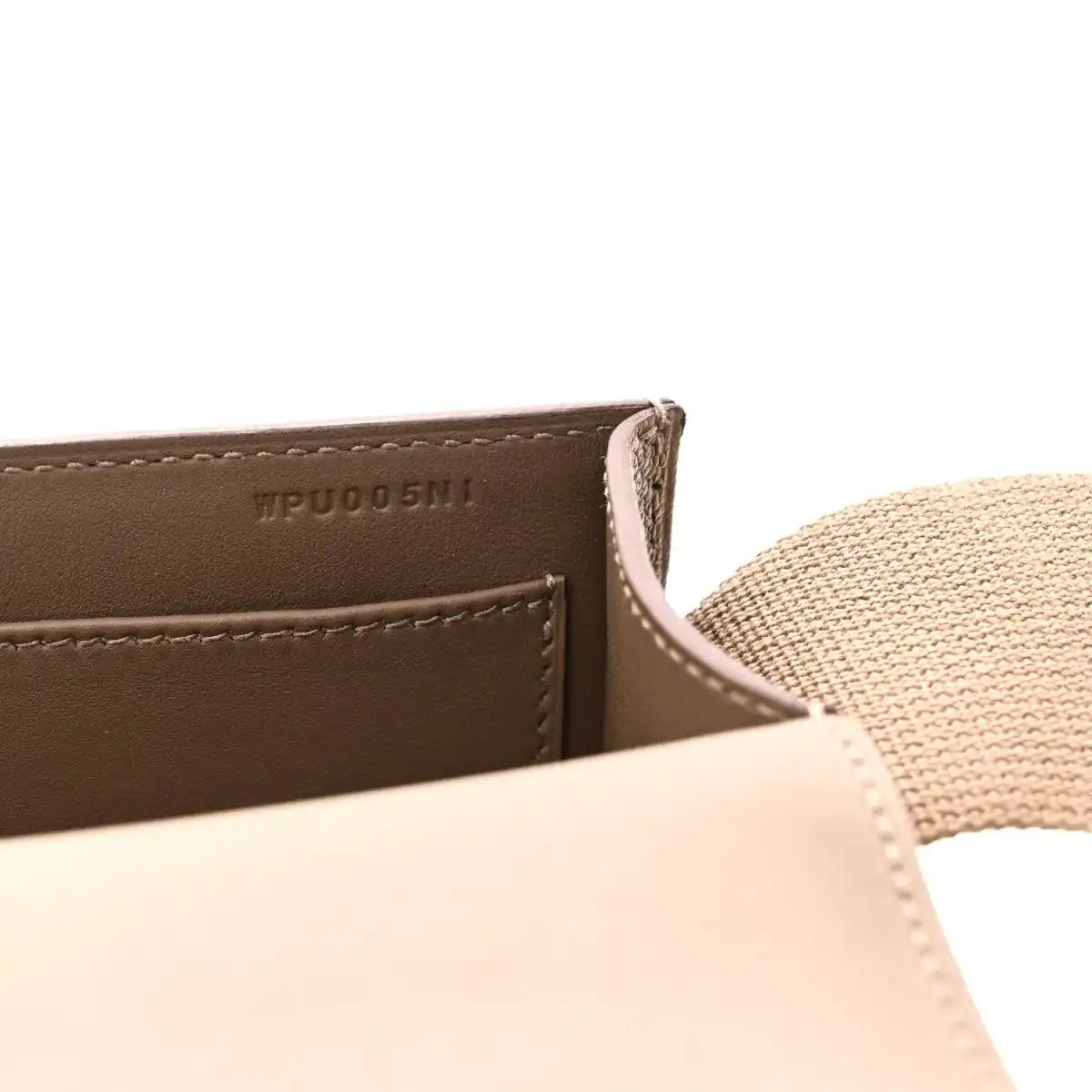Close-up of taupe leather messenger bag label and stitched edge with strap
