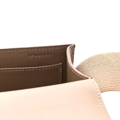 Close-up of taupe leather messenger bag label and stitched edge with strap