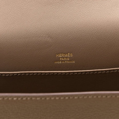 Taupe leather bag panel with embossed brand text and contrast edge stitching