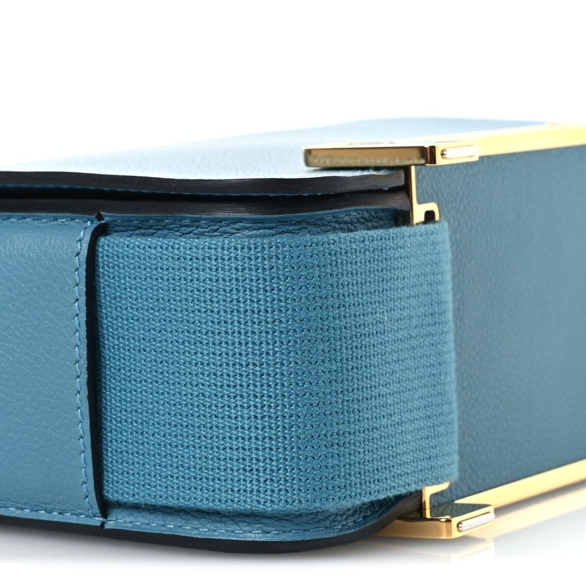Blue leather messenger bag close-up of interior pocket under open flap and gold hardware.