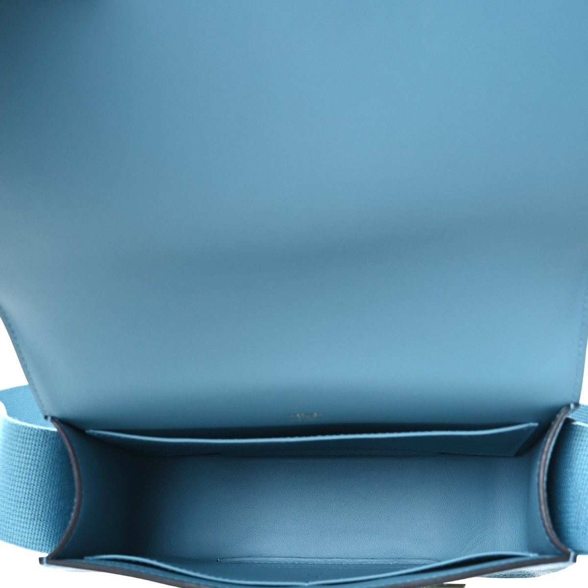 Blue leather bag interior with flap opening and stitched lining edge.