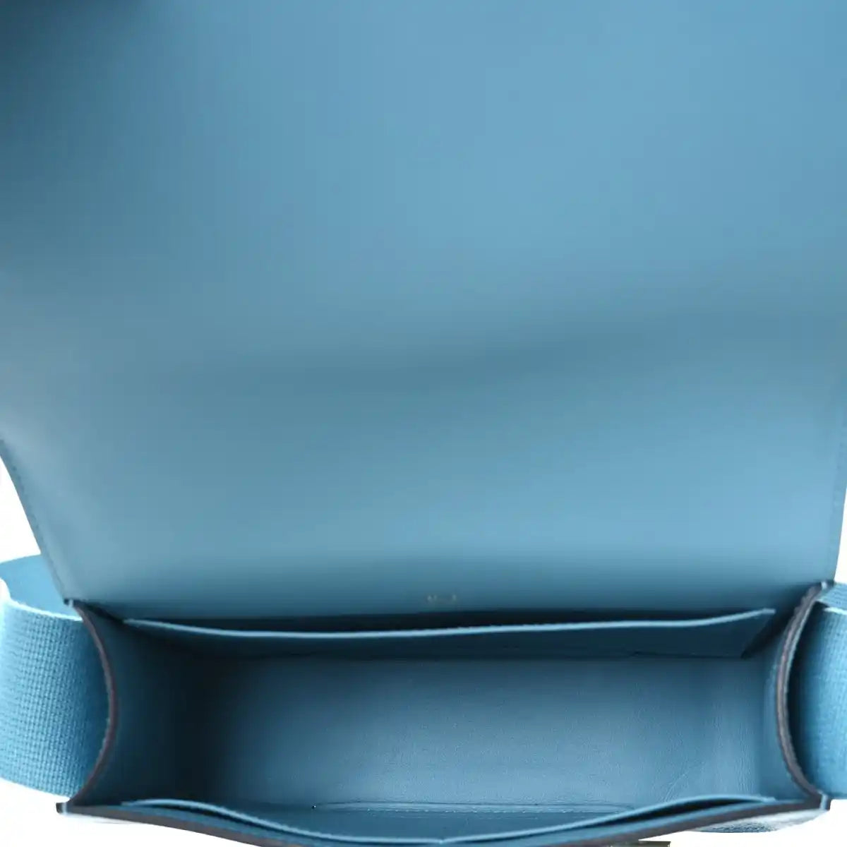Blue leather bag interior with flap opening and stitched lining edge.