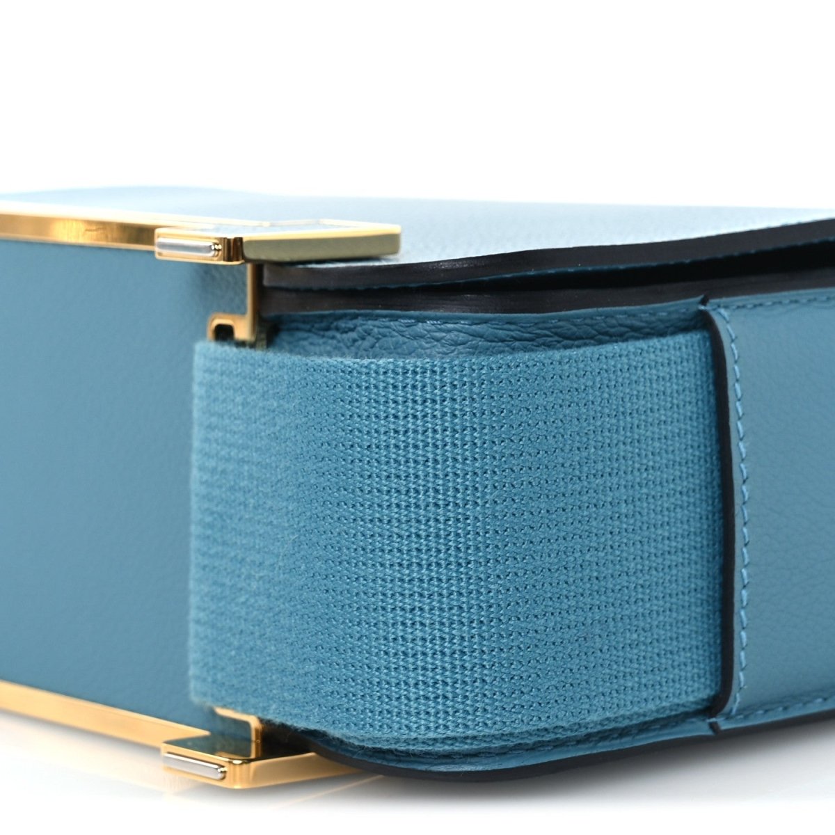 Blue leather flap pocket close-up with gold-tone clasp bar and stitched trim.