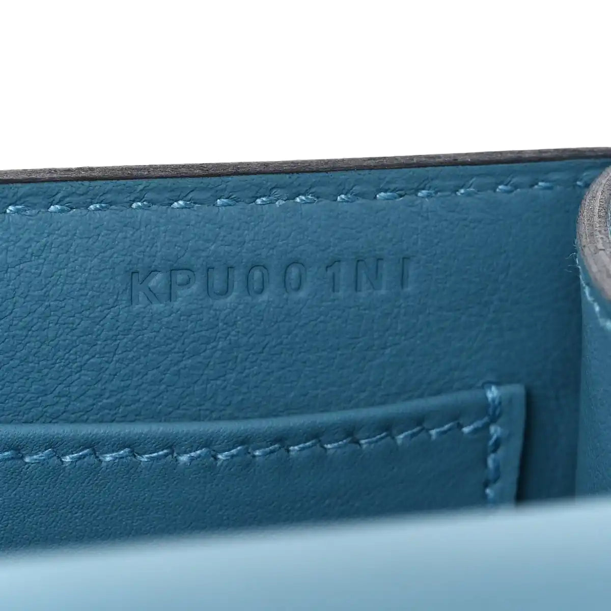 Blue leather bag with embossed code and visible stitched seam detail.