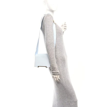 Light blue leather crossbody strap with grey underside and metal hardware