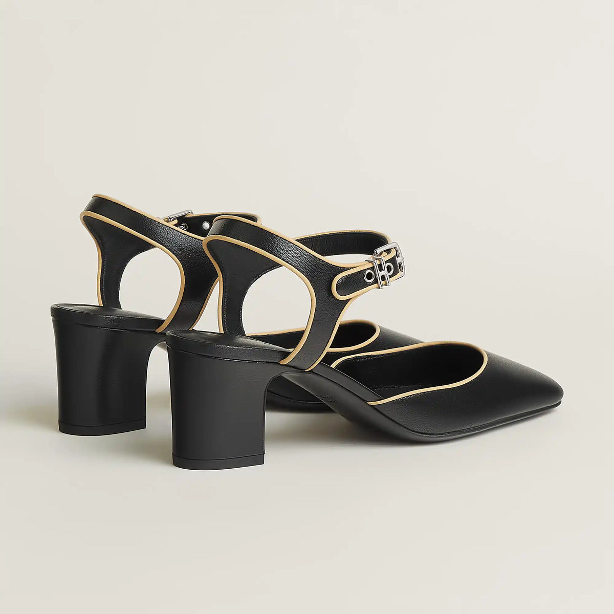 Black Mary Jane pump with ankle strap and gold buckle, cutout vamp, block heel.
