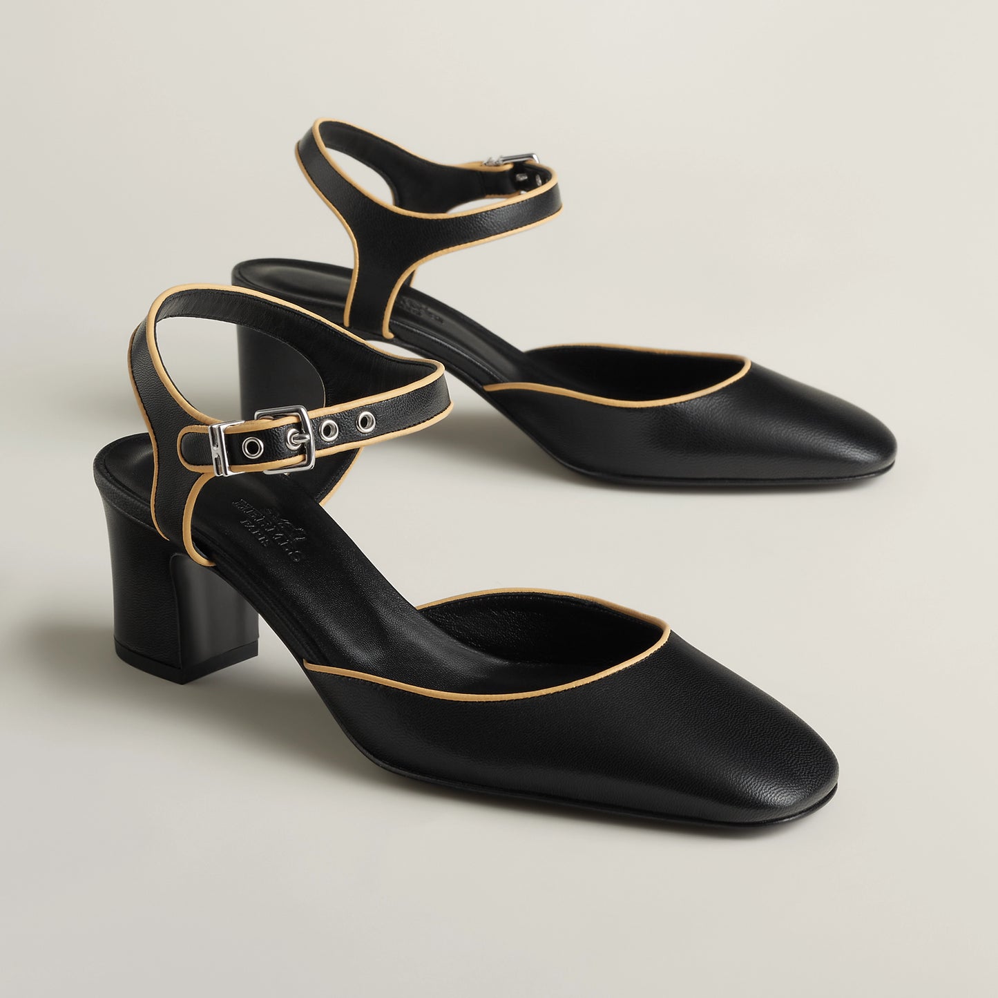 Black Mary Jane pump with ankle strap, gold buckle, block heel, pointed toe.