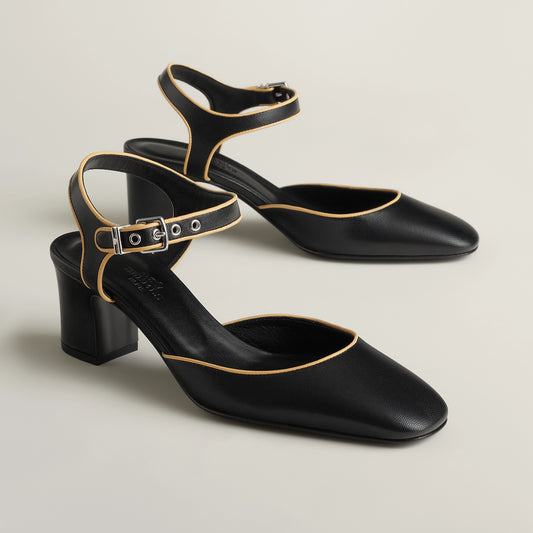 Black Mary Jane pump with ankle strap, gold buckle, block heel, pointed toe.