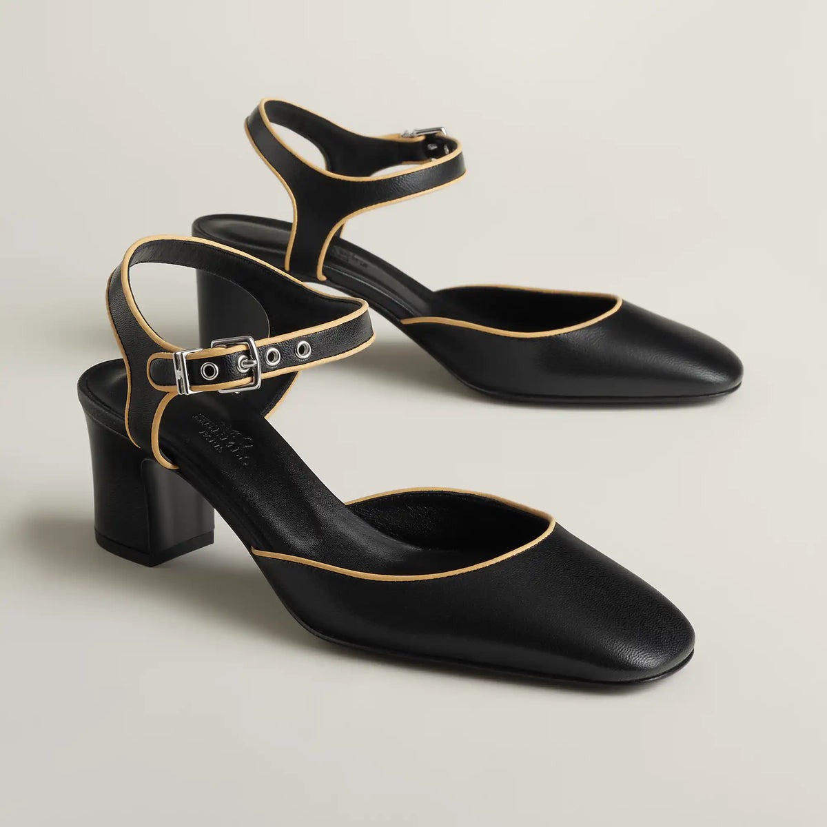 Black Mary Jane pump with ankle strap, gold buckle, block heel, pointed toe.