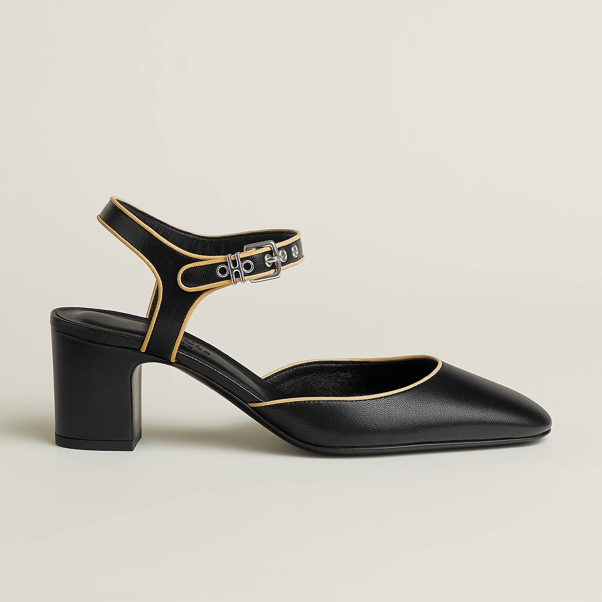 Black Mary Jane pump showing ankle strap and gold buckle, block heel, pointed toe.