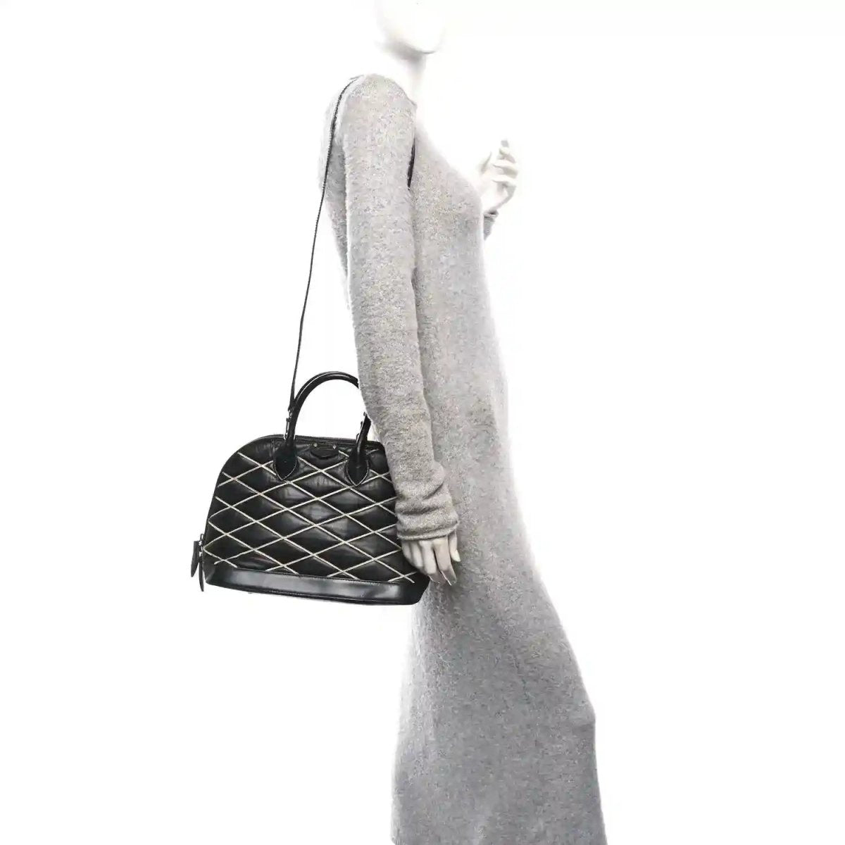Black quilted Alma PM handbag held by top handles, gold-tone zipper pull