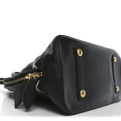 Black leather handbag side view with gold-tone studs and short strap