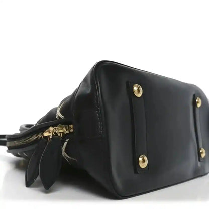 Black leather handbag side view with gold-tone studs and short strap
