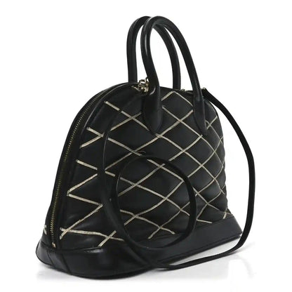Black quilted handbag with rounded top, dual handles, gold-tone eyelets