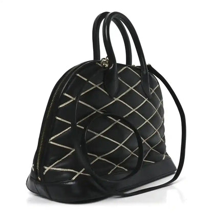 Black quilted handbag with rounded top, dual handles, gold-tone eyelets
