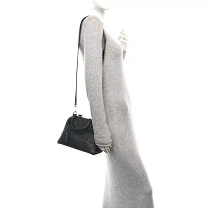 Black leather mini handbag on a crossbody strap, shown from side