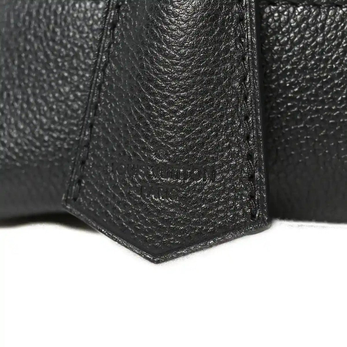 Black leather handbag corner with textured grain and reinforced seams
