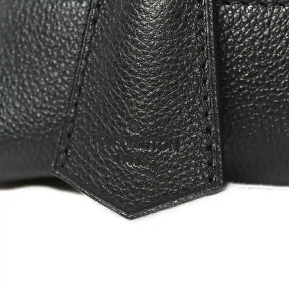 Black leather handbag corner with textured grain and reinforced seams