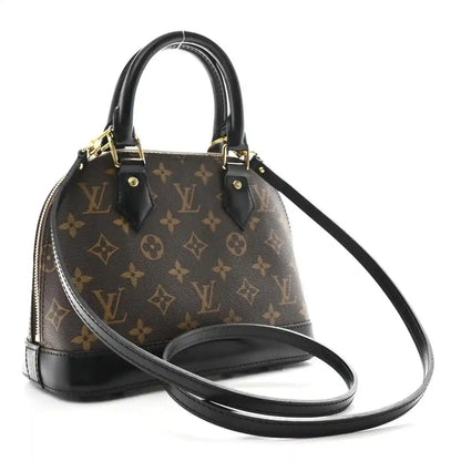 Small monogram tote with black leather trim, top handles, and long crossbody strap