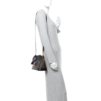 Small monogram tote worn on a person, side view with black strap and top handles