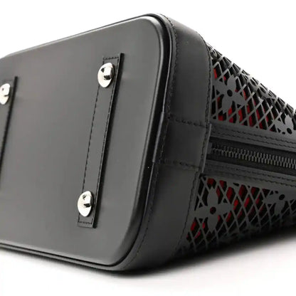 Black patent leather handbag with silver studs, monogram laced side, and zipper opening