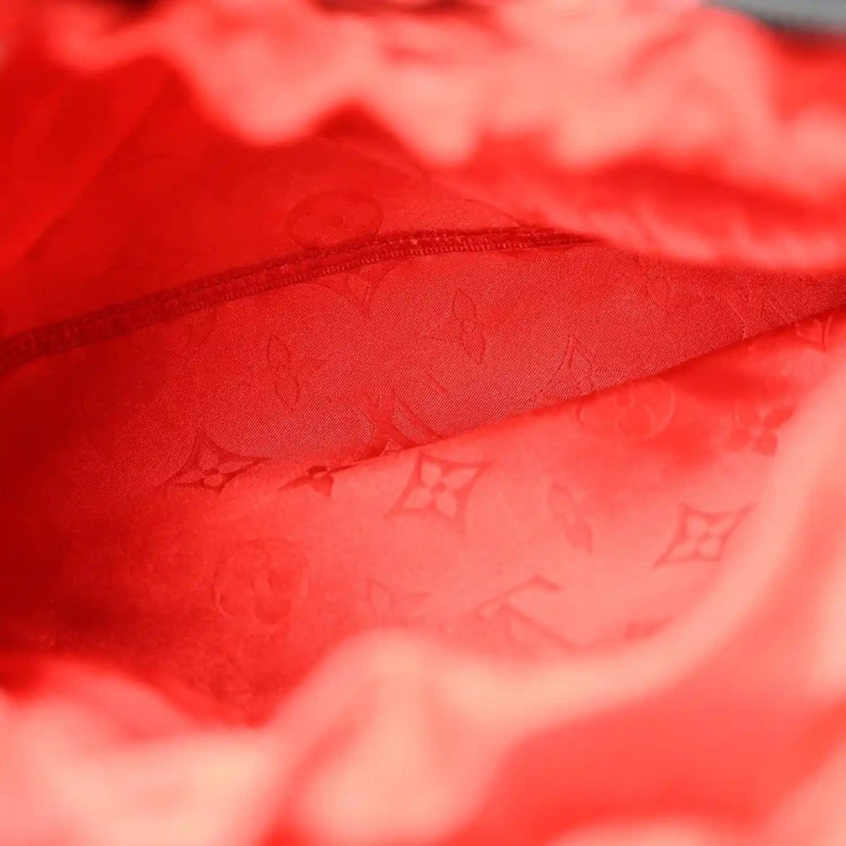 Red monogram-lined handbag interior with zip edge, fabric close-up