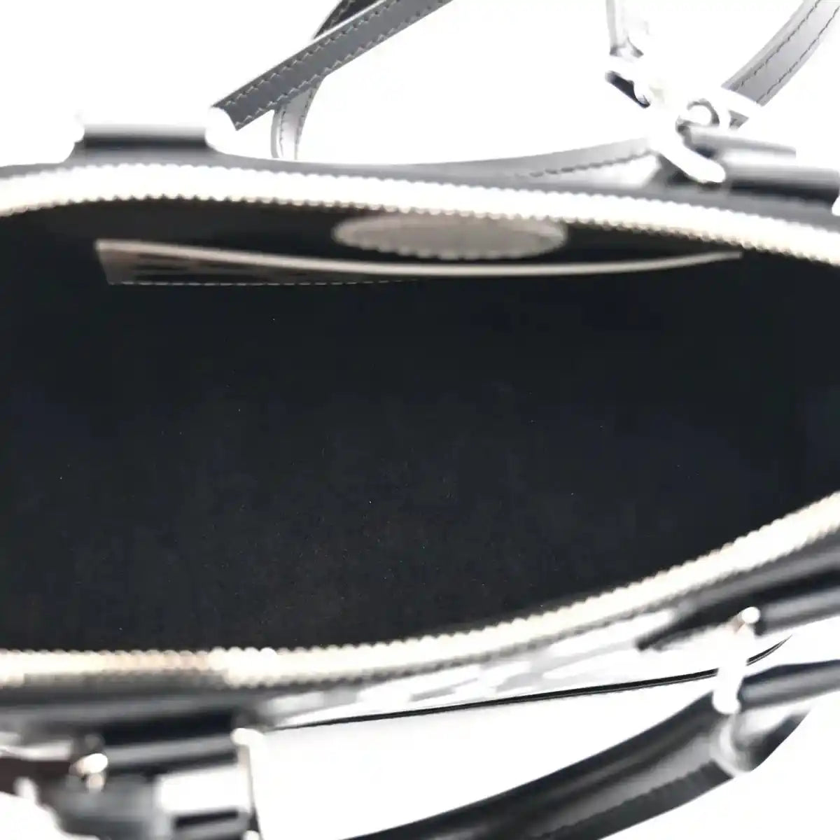 Alma BB bag zipper close-up with metal teeth and black leather trim over interior lining