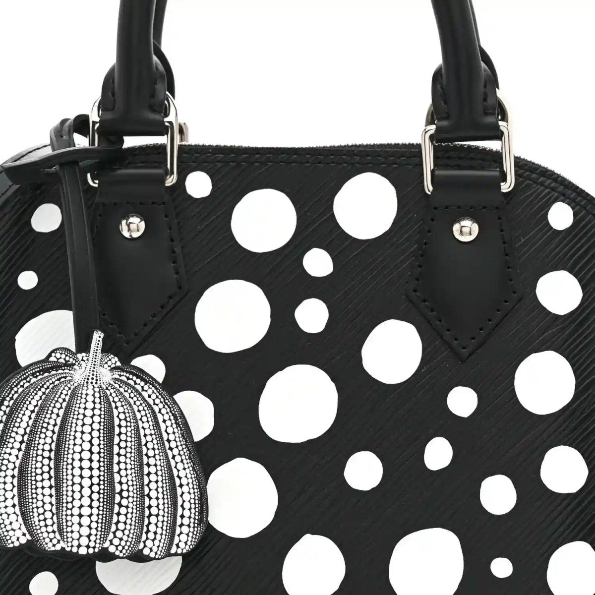Alma BB bag front with white polka dots, black top handles, and pumpkin charm on clip