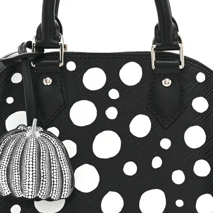 Alma BB bag front with white polka dots, black top handles, and pumpkin charm on clip