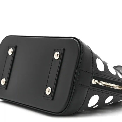 Alma BB bag angled side with smooth black panel, silver studs, and polka-dot trim